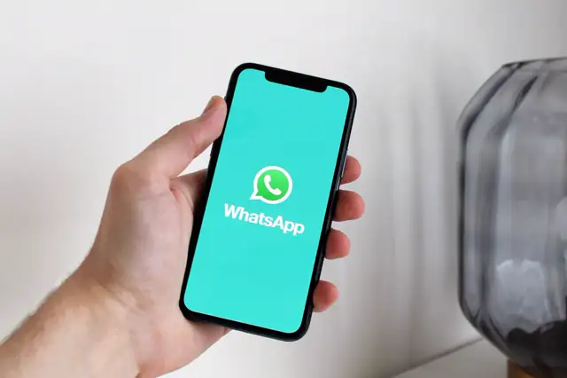 Mão segurando um celular com o WhatsApp aberto